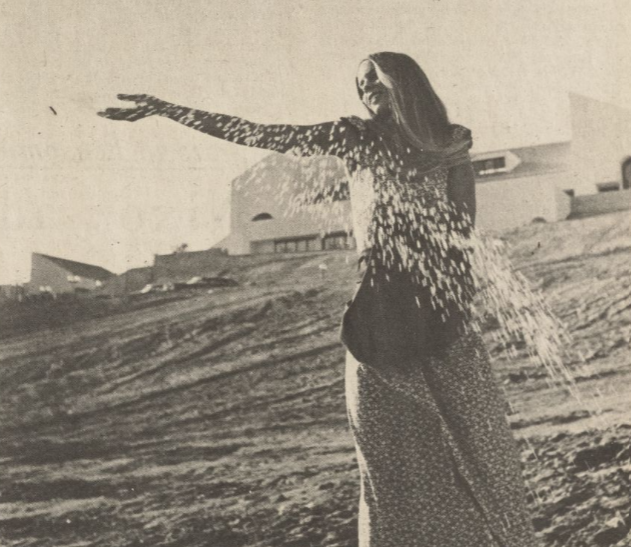 A student sows grass on a barren campus hillside.